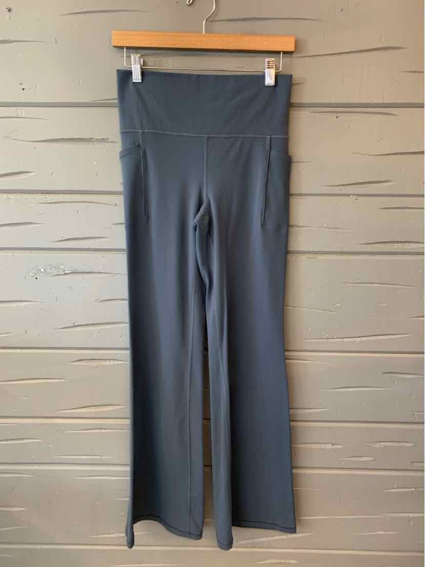 Dark blue high-waisted athletic leggings with wide waistband and flared legs on wooden hanger.
