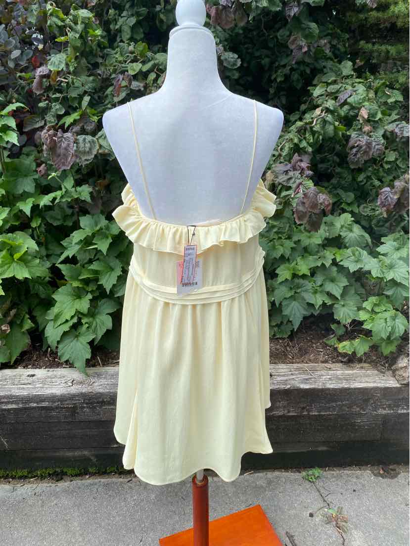 Light yellow sleeveless dress with ruffled top and thin adjustable straps on mannequin outdoors.
