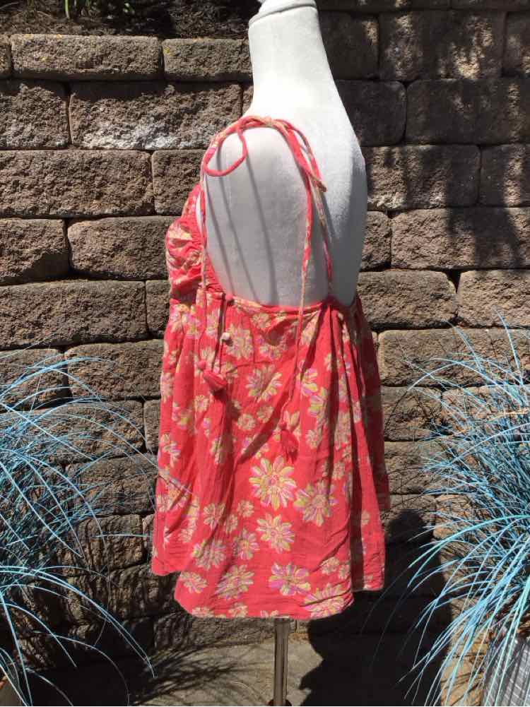 Coral sleeveless dress with white and yellow floral print and thin adjustable straps on mannequin.