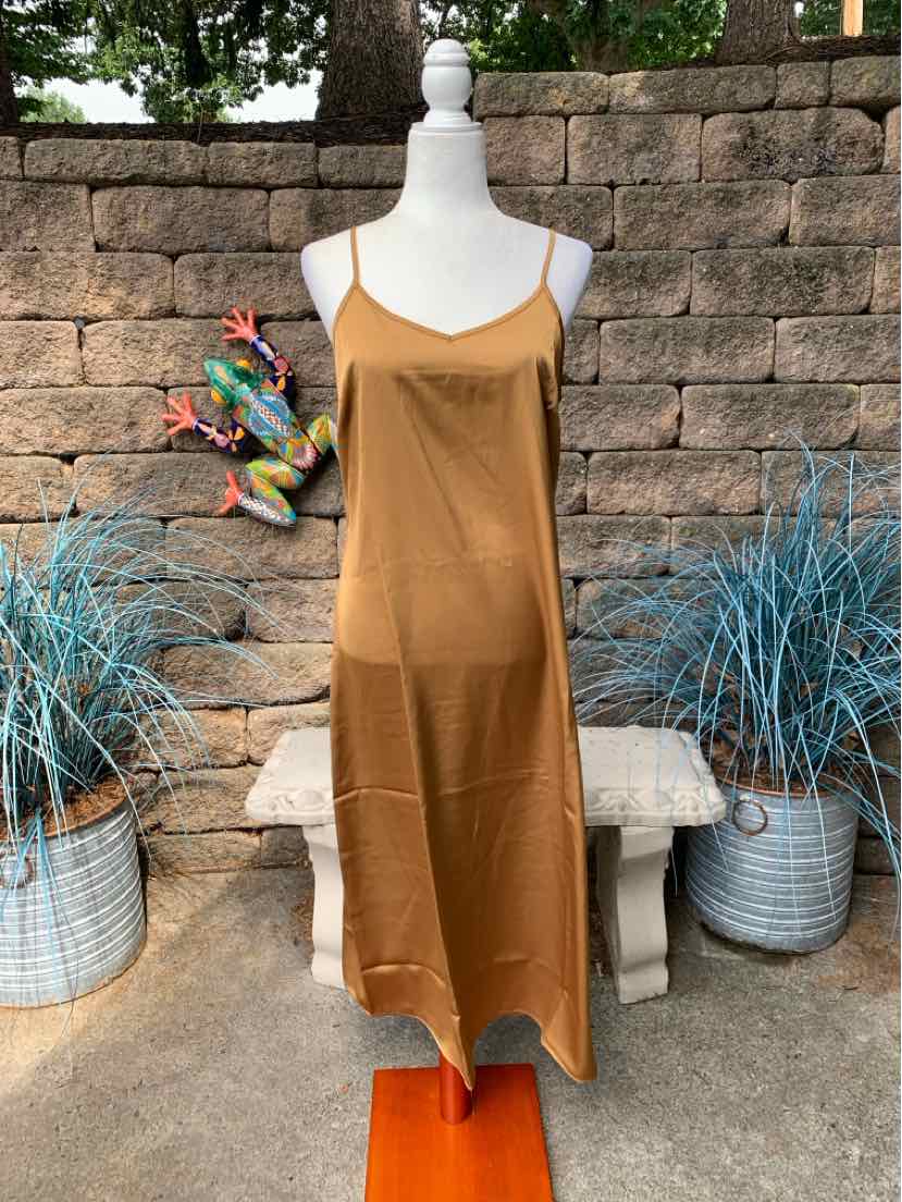 Sleeveless tan midi slip dress with thin straps and a straight hem on a mannequin outdoors.