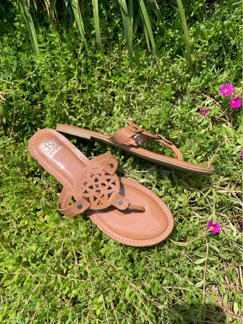 Tan leather thong sandals with a decorative cutout flower design and a flat sole.