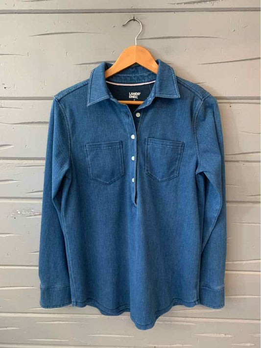 Long-sleeve medium blue shirt with collar, button placket, and two chest pockets hanging on wooden hanger.