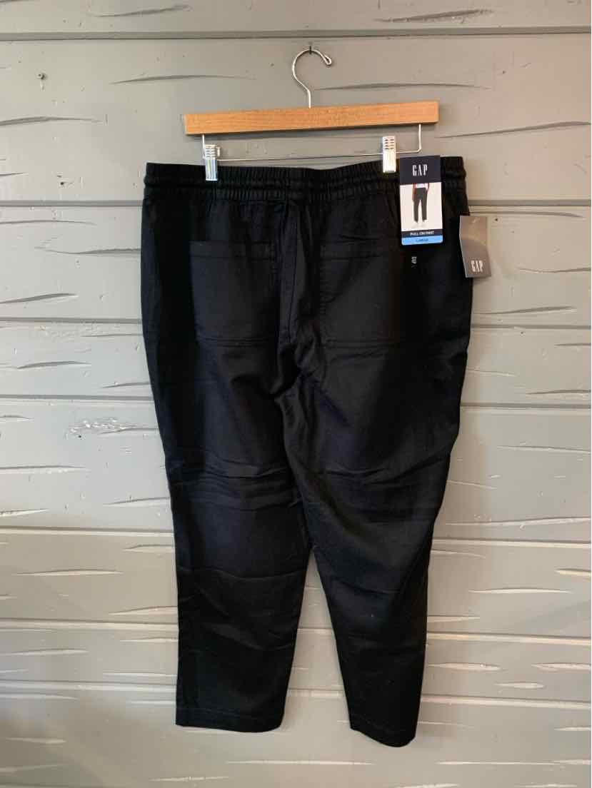 Black mid-rise pants with tapered legs and elastic waistband hanging on wooden hanger.