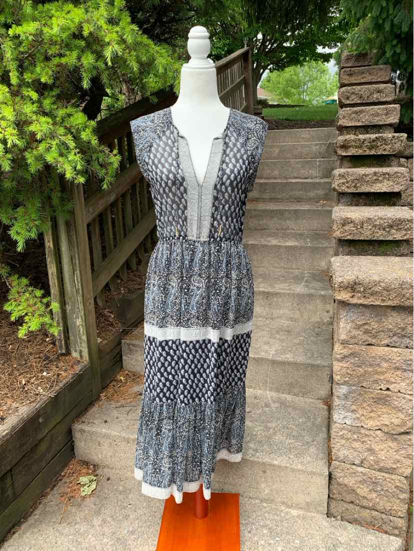Sleeveless tiered maxi dress with navy and white paisley print and V-neckline on mannequin outdoors.
