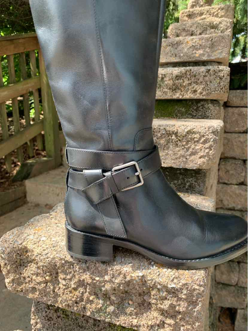 Black leather knee-high boot with side buckle strap and low block heel.