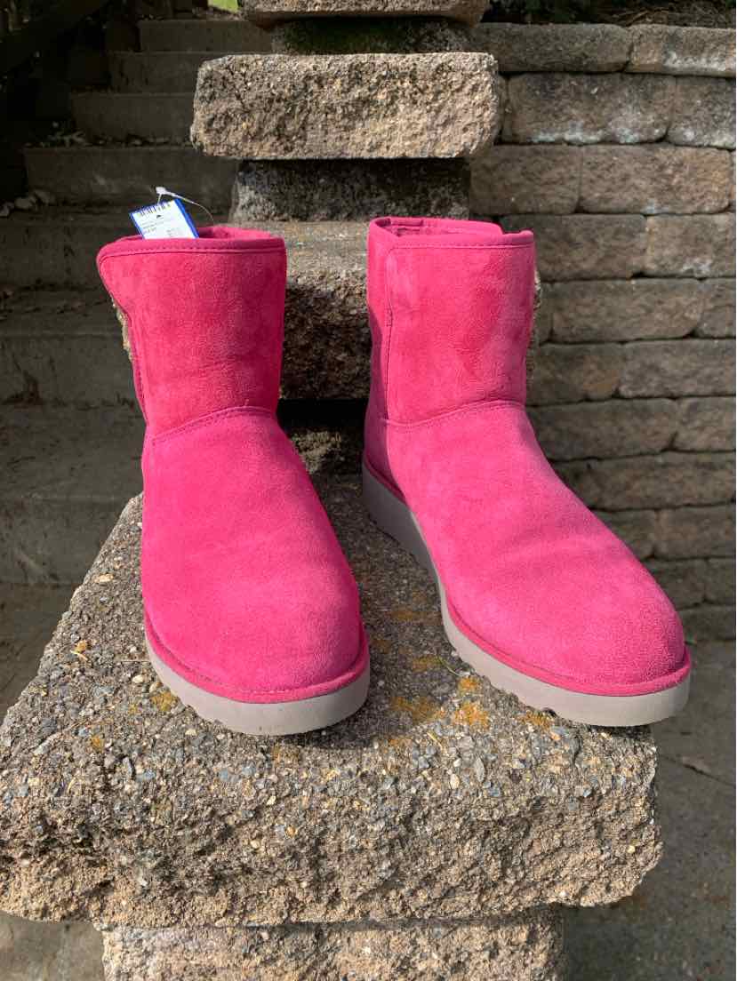 Pair of bright pink suede UGG boots with rounded toes, plush lining, and flat beige soles.