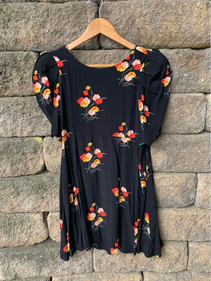 Black short dress with puff sleeves and small red and yellow floral print.