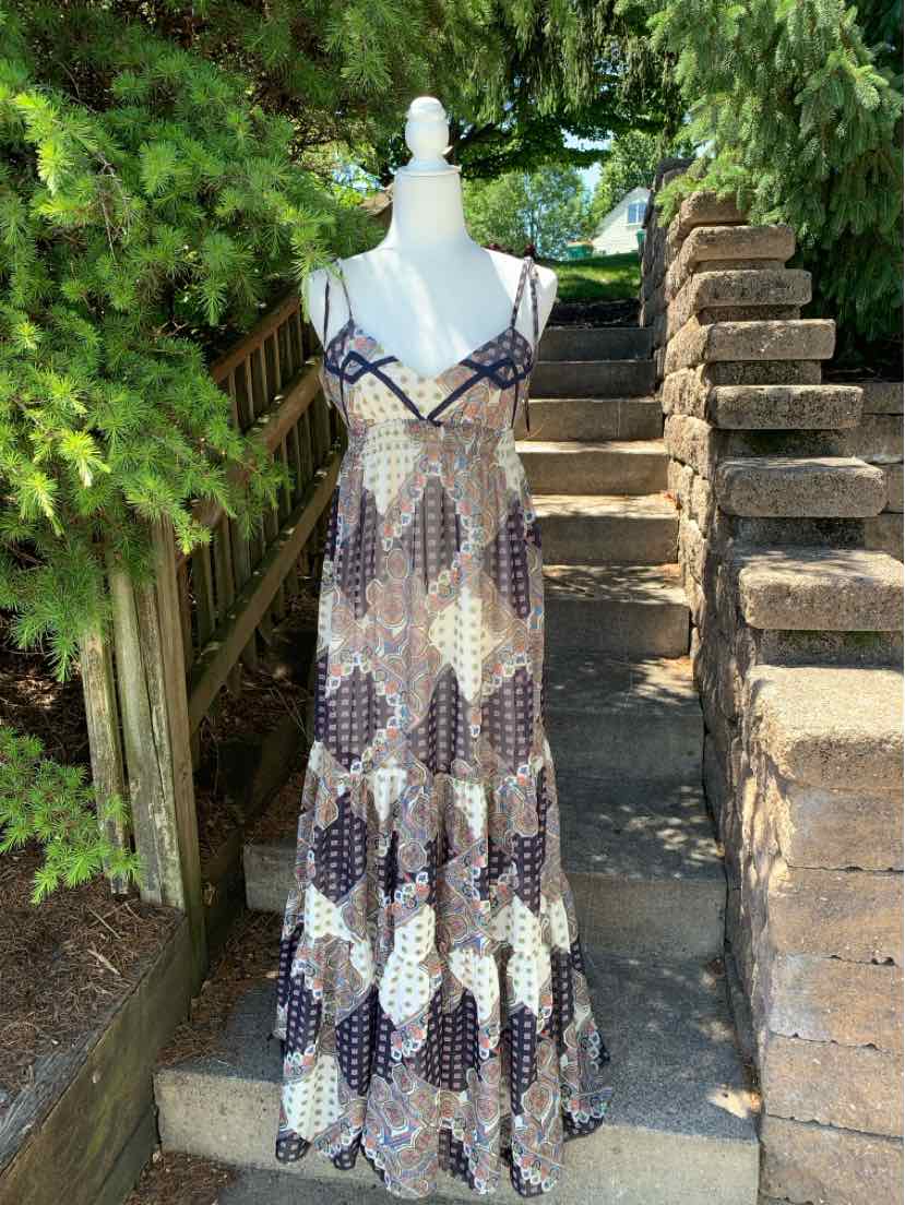 Long paisley maxi dress in shades of brown and cream with thin black straps and V-neckline.