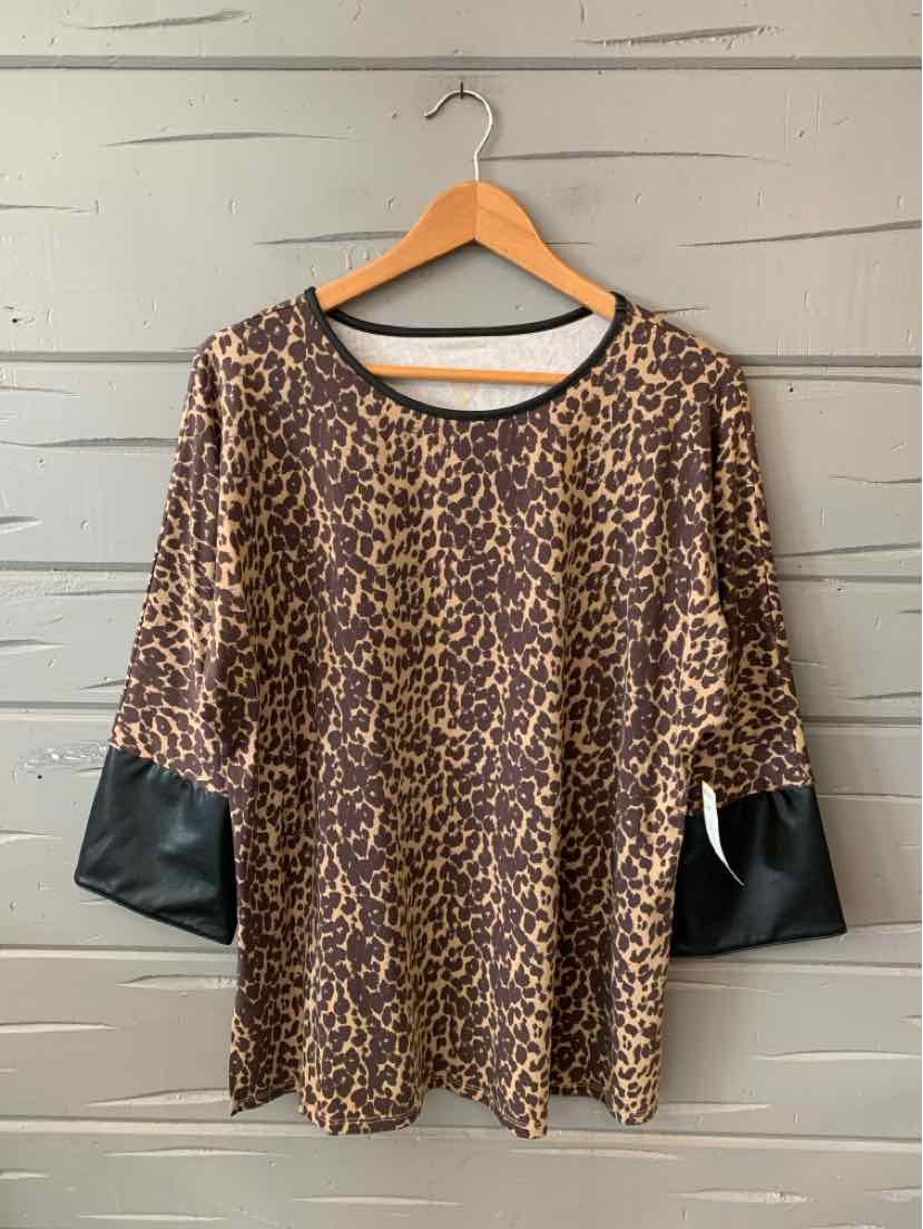 Leopard print blouse with black faux leather elbow patches and round neckline hanging on wooden hanger.