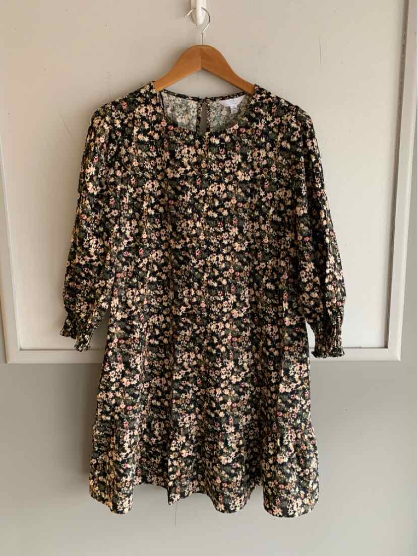 Black long-sleeve dress with small beige and pink floral print and tiered skirt.