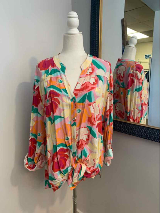 Colorful floral blouse with a mix of red, pink, orange, and green on a light background, featuring a V-neck and long.