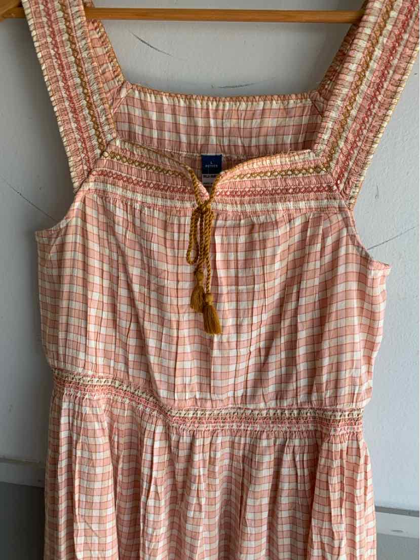 Sleeveless peach and white gingham dress with smocked bodice and tasseled tie neckline.