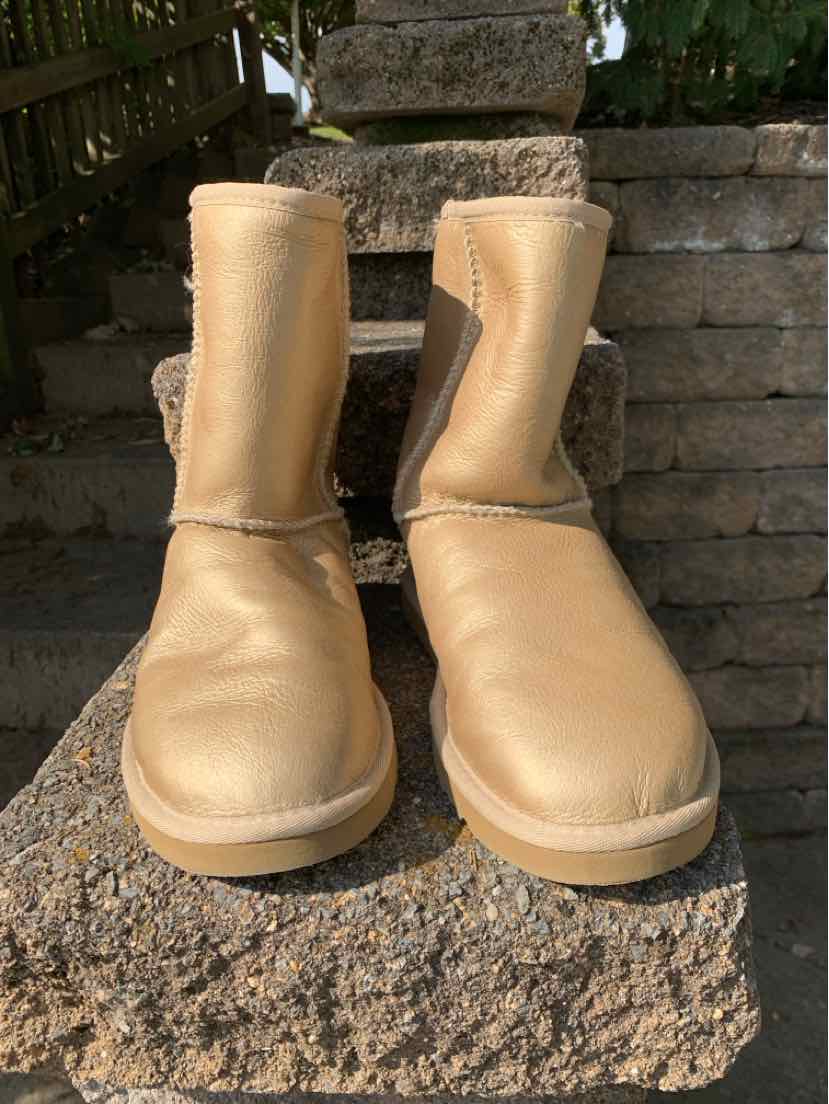 Pair of tan UGG boots with soft suede uppers, rounded toes, and thick cream soles.