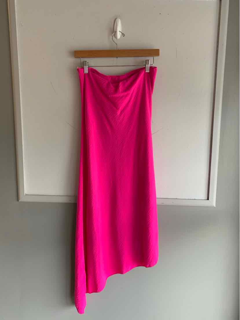 Bright pink asymmetrical midi skirt with a smooth, flowing fabric hanging on a wooden hanger.