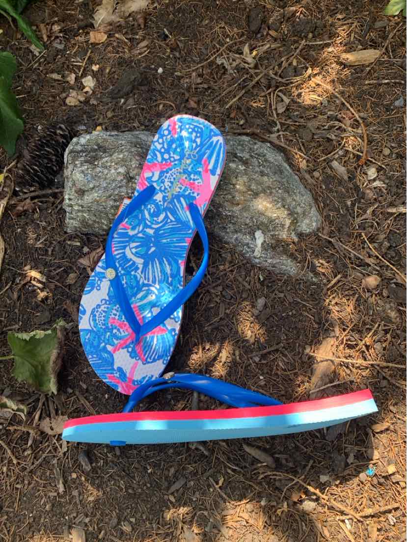 Blue flip-flop sandal with pink and white tropical floral pattern and layered sole in blue, white, and red.
