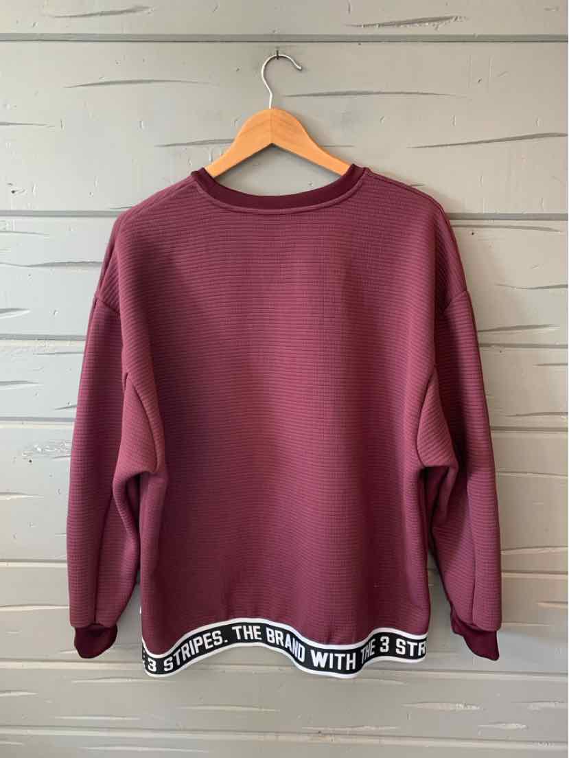 Burgundy crewneck sweatshirt with black and white elastic band reading "THE BRAND WITH 3 STR" at hem.