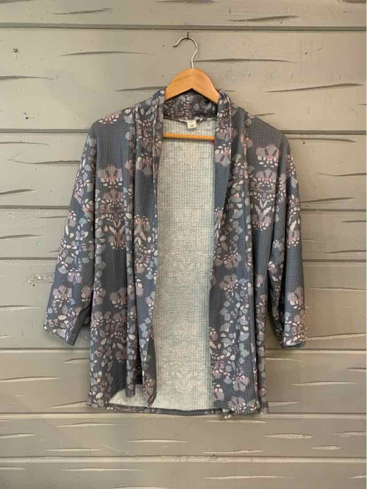 Gray floral open-front cardigan with three-quarter sleeves on wooden hanger.