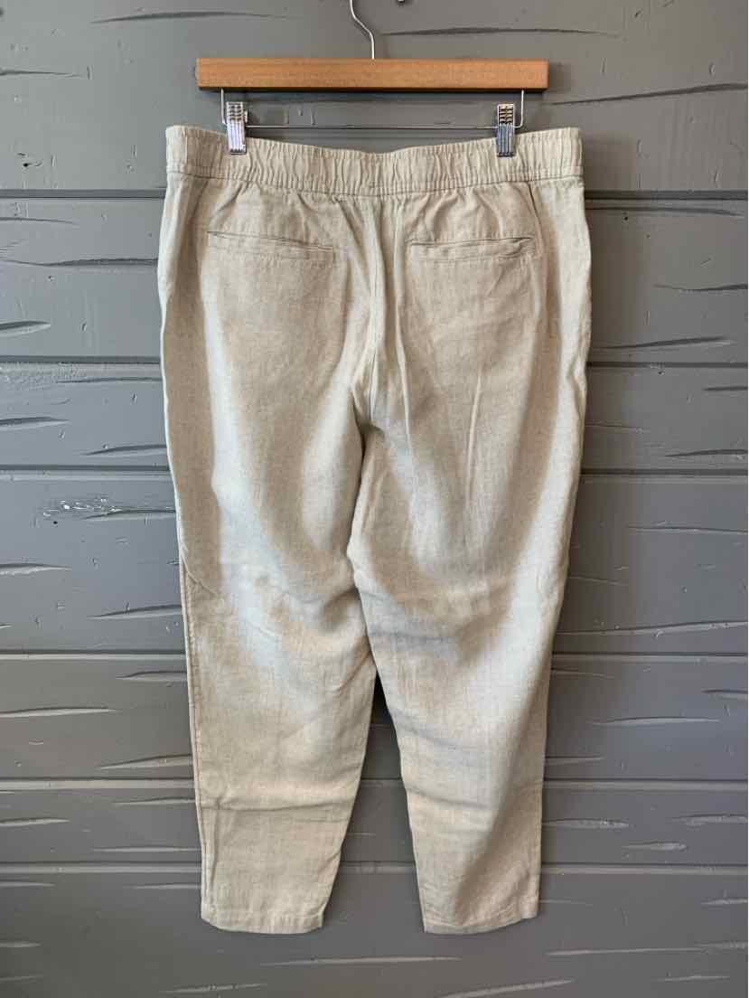 Beige casual pants with elastic waistband and tapered legs hanging on wooden hanger.