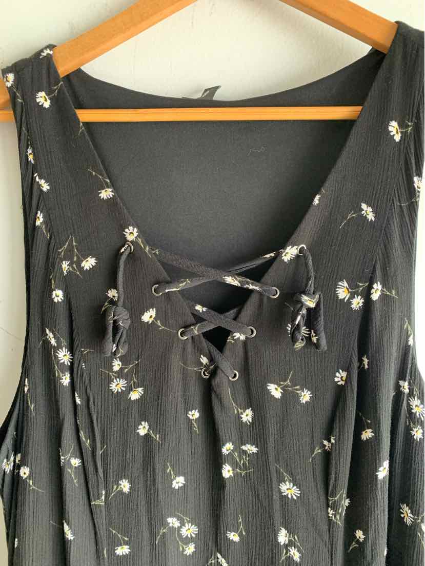 Black floral dress with lace-up neckline and short sleeves hanging on wooden hanger.