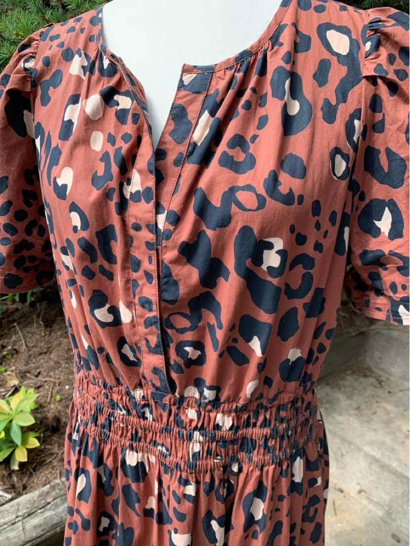 Rust-colored dress with bold black and beige cheetah spots, puffed sleeves, elastic waist, and a front button placket.
