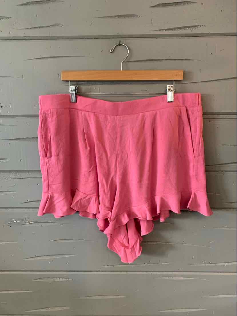 Pink lightweight shorts with ruffled hem and elastic waistband hanging on wooden hanger.