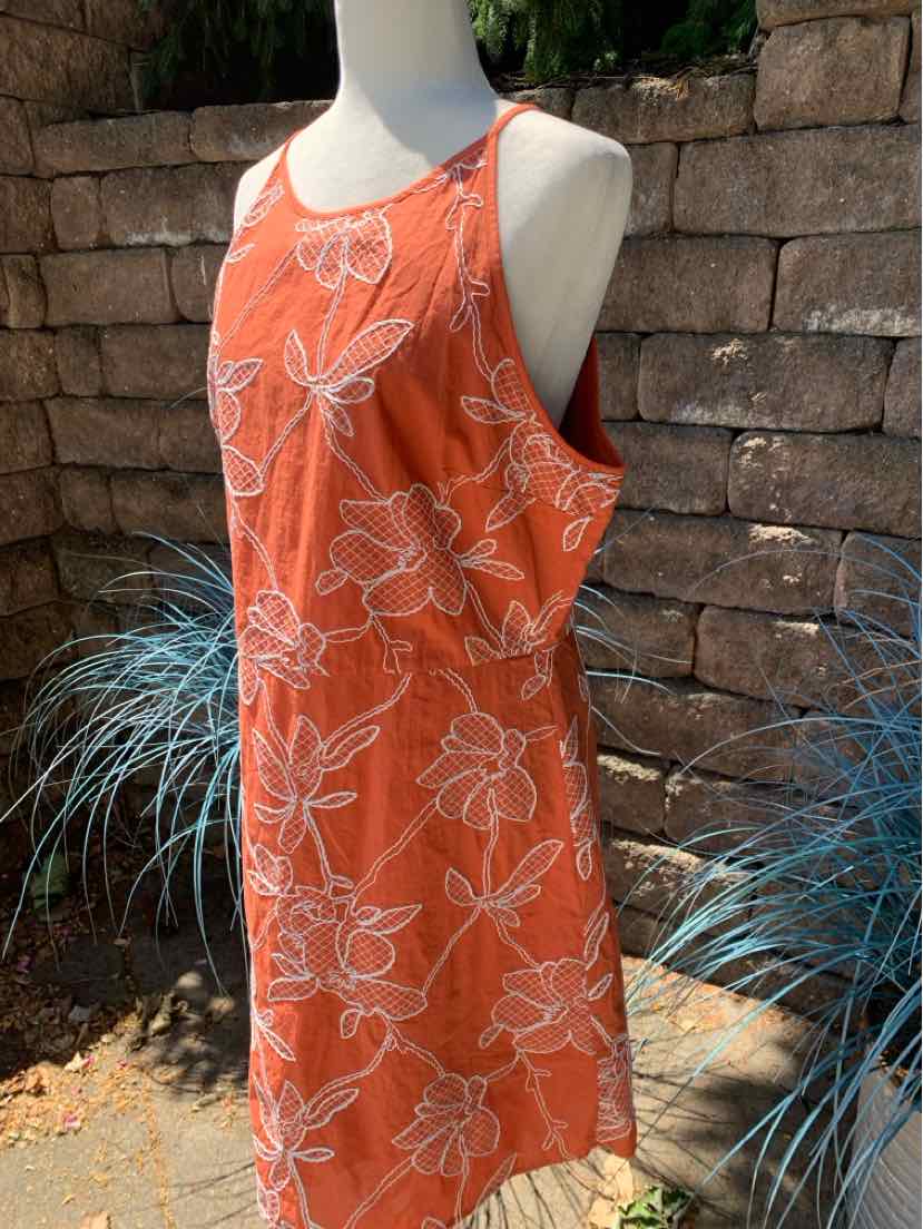 Orange sleeveless dress with white floral print and scoop neckline, knee-length silhouette.
