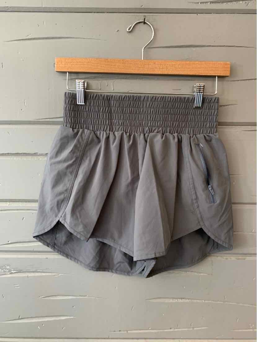 Gray high-waist shorts with wide smocked waistband and curved hem hanging on wooden hanger.
