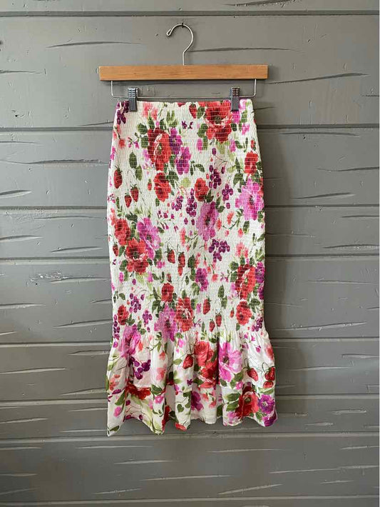 Floral multi-color midi skirt with ruffled hem in lightweight fabric hanging on wooden hanger.