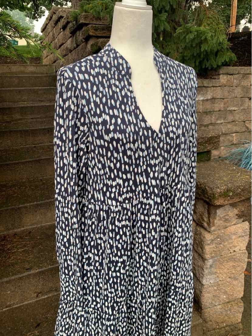 Navy blue sleeveless dress with white irregular polka dots and V-neckline on mannequin.