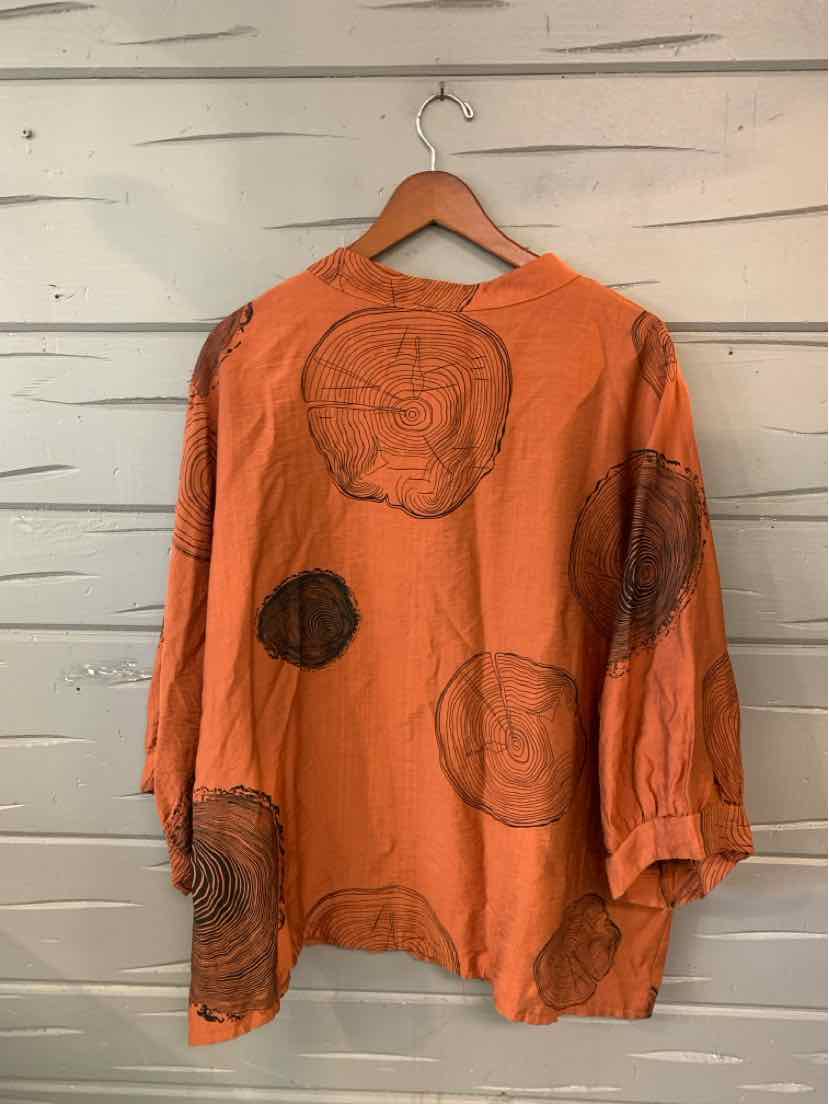 Oversized long-sleeve orange blouse with large abstract circular prints, loose fit, lightweight fabric.