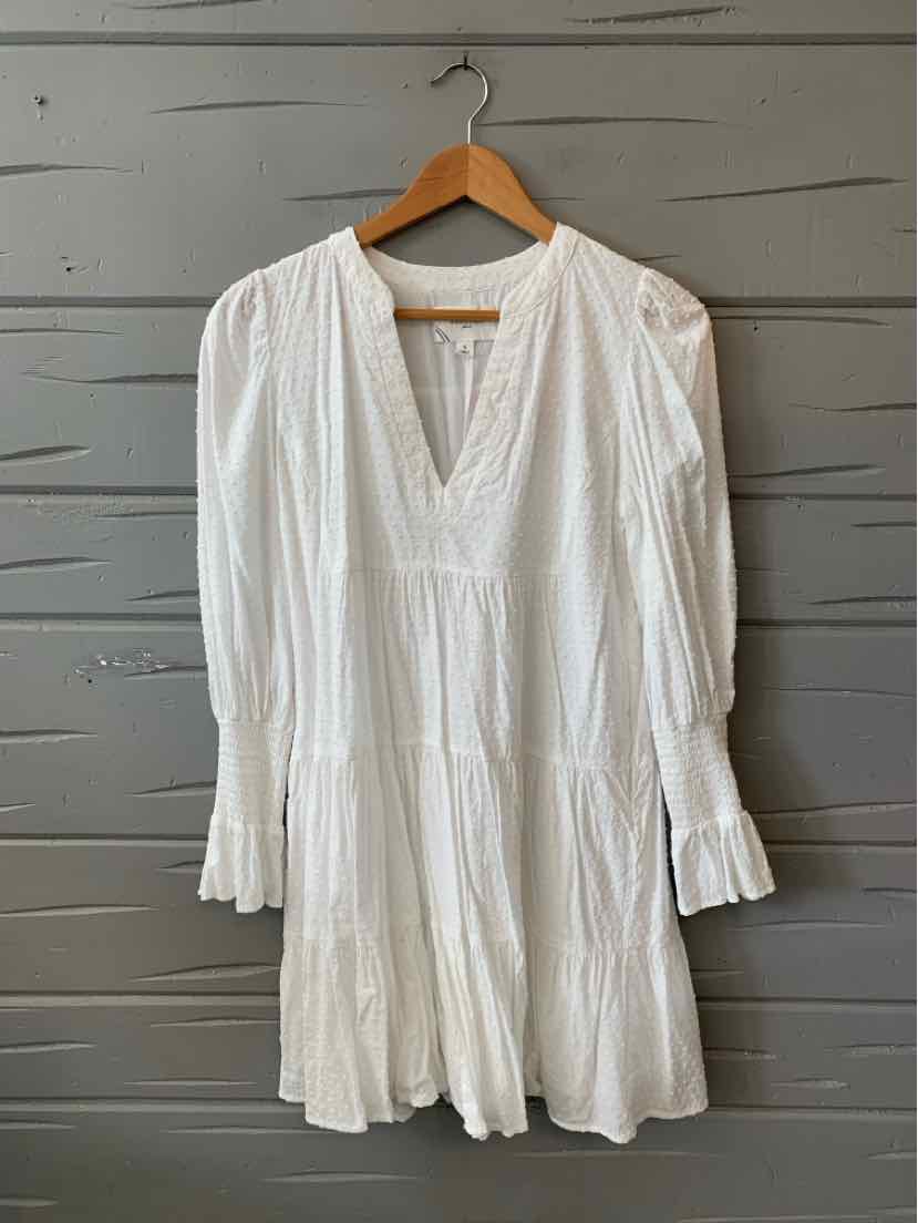 White long-sleeve dress with v-neckline, gathered fabric details, and tiered skirt on wooden hanger.