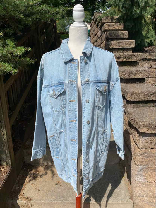Light blue denim jacket with button front, chest pockets, and long sleeves on a dress form outdoors.