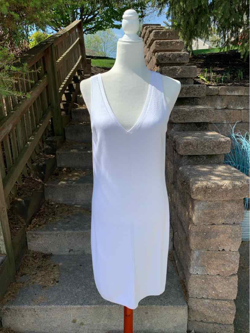 White sleeveless knit dress with V-neck and fitted silhouette on mannequin outdoors.