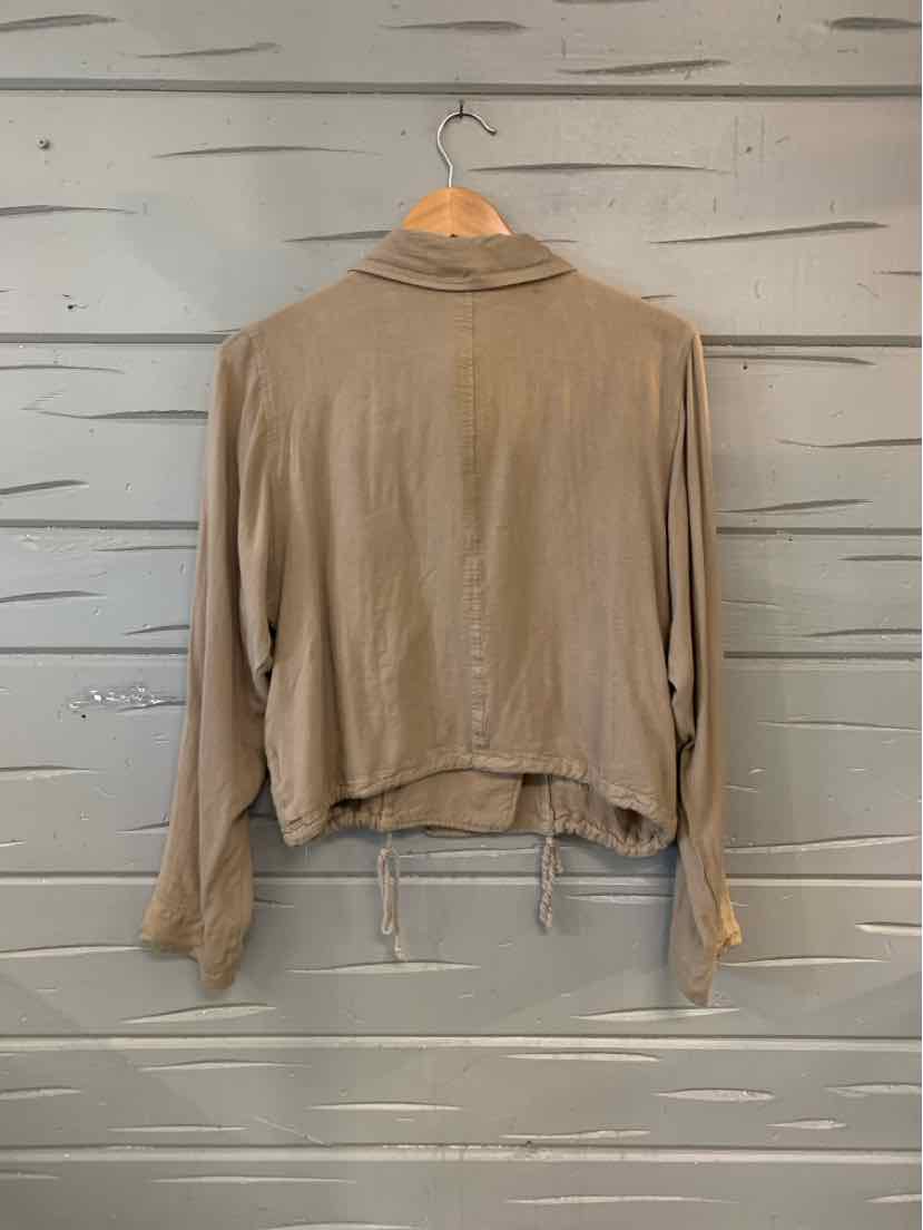 Light brown long-sleeve cropped jacket with drawstring hem and relaxed fit hanging on wooden hanger.