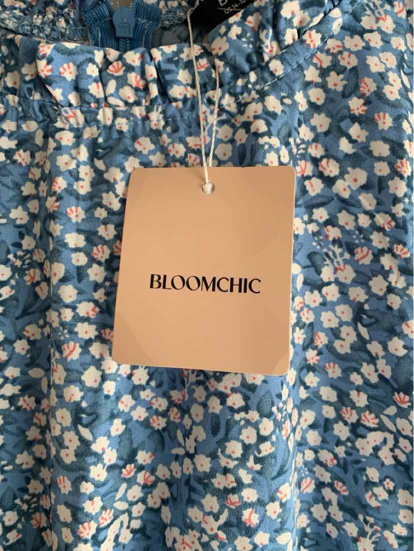 Blue fabric with small white and pink floral print, elastic waistband, beige Bloomchic tag attached.