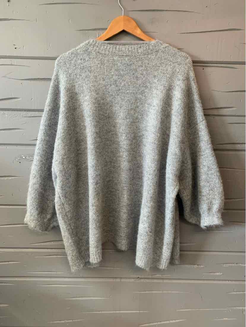 Light gray soft knit cardigan with long sleeves and relaxed fit hanging on wooden hanger.