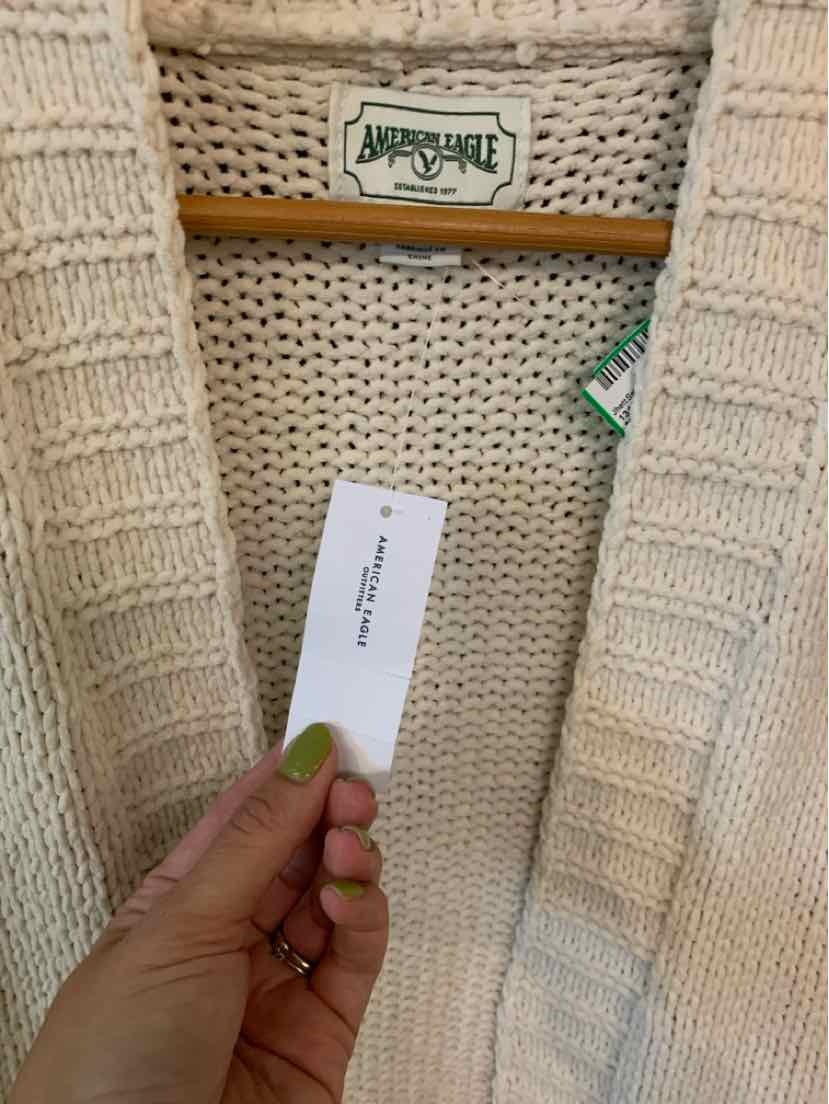 Cream-colored chunky knit cardigan with ribbed collar and open front design.