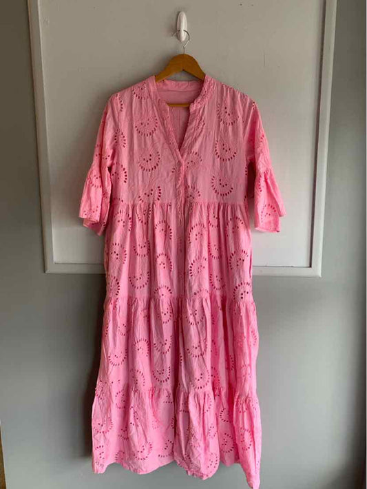 Pink tiered midi dress with eyelet embroidery, V-neckline, and 3/4 ruffled sleeves.