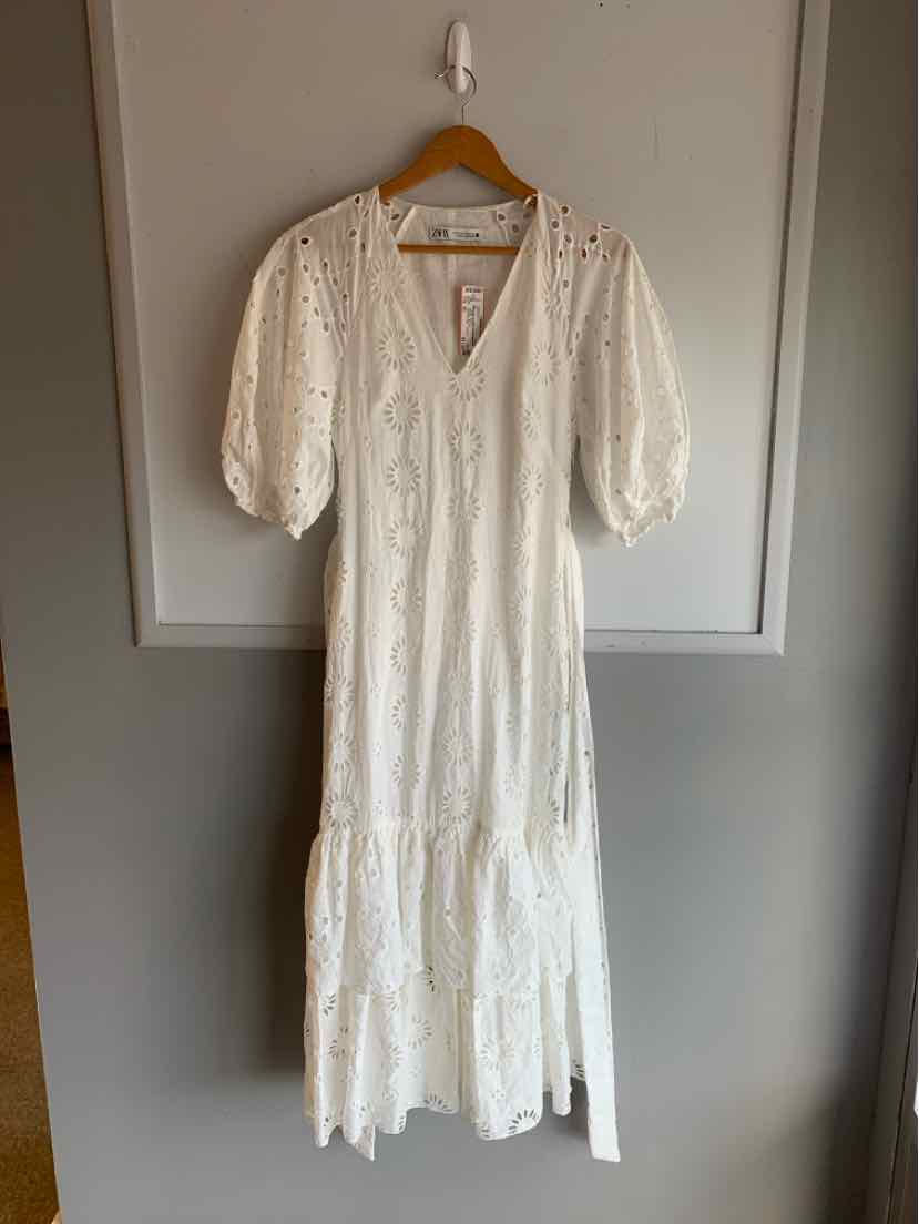 White eyelet midi dress with puff sleeves, V-neck, and tiered hem.