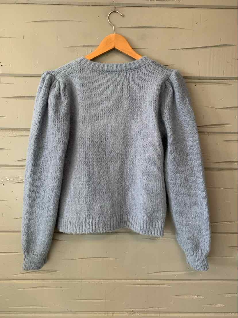 Light gray knit sweater with long sleeves, ribbed crew neck, cuffs, and hem, hanging on a wooden hanger.