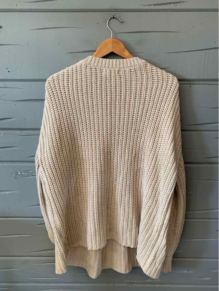 Oatmeal knit sweater with a chunky ribbed texture, relaxed fit, and long sleeves.