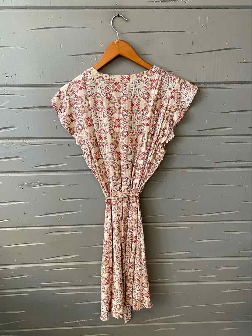 Pink paisley-print lightweight dress with short flutter sleeves and gathered waist on wooden hanger.