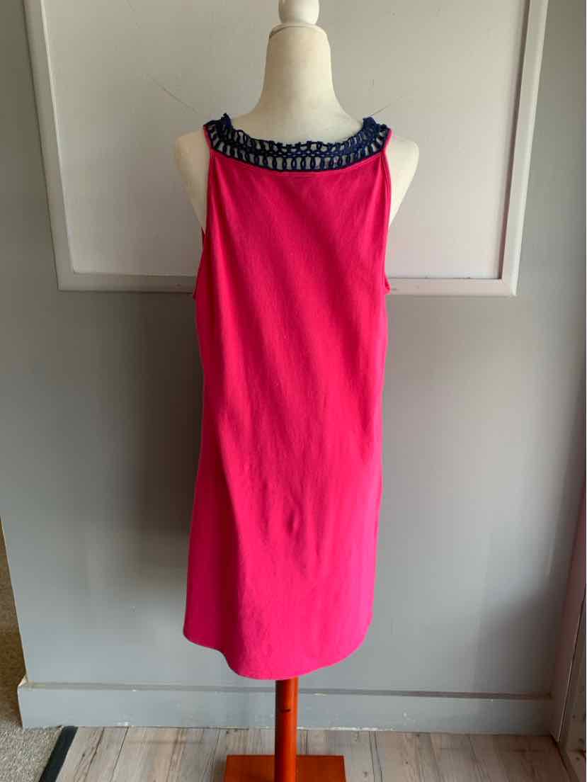 Bright pink sleeveless dress with navy blue ruffled neckline on dress form against gray wall.