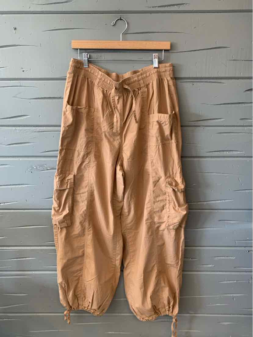 Tan cargo pants in large size with elastic cuffs and multiple front and side pockets.