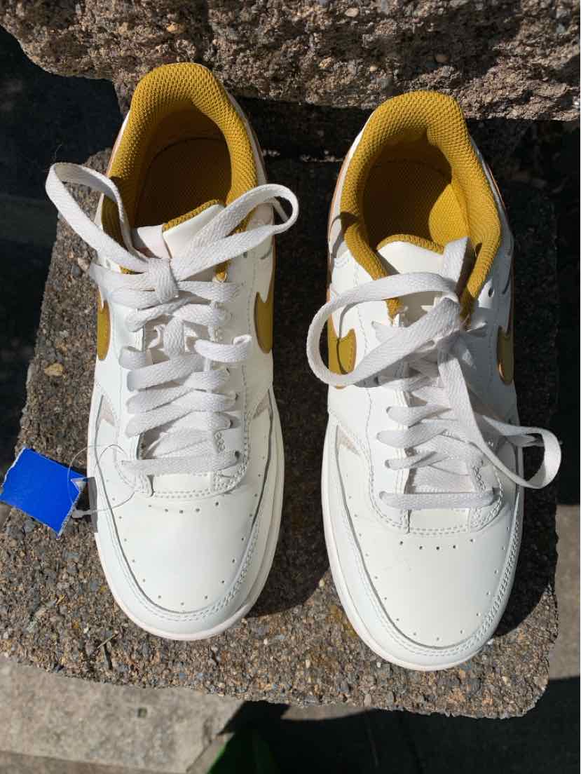 White Nike sneakers with solid yellow interior lining and white laces, size 8.