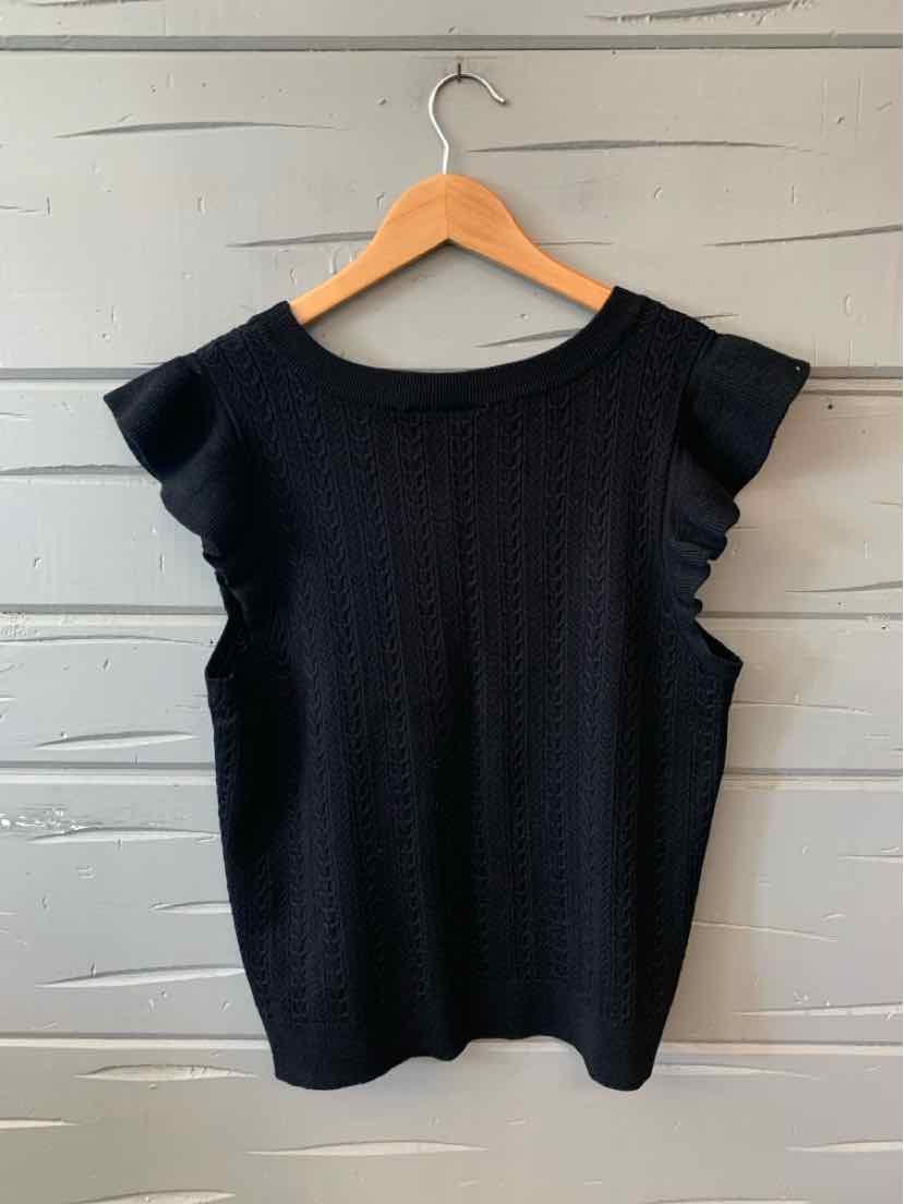 Black knit sleeveless top with ruffled shoulder details and round neckline on wooden hanger.