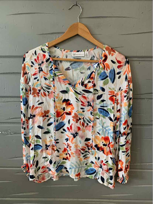 Lightweight blouse with vibrant multicolor floral pattern, V-neck, and long sleeves on wooden hanger.