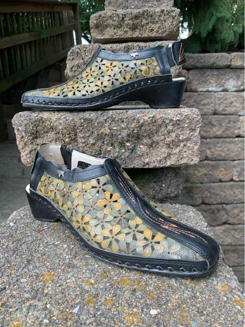 Black leather wedge shoes with yellow floral cutout pattern and front zipper closure.