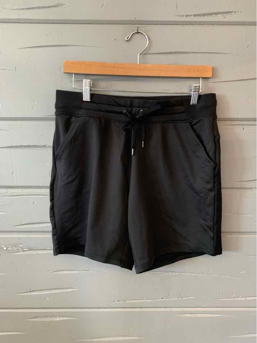 Black mid-length athletic shorts with drawstring waist and side pockets hanging on wooden hanger.