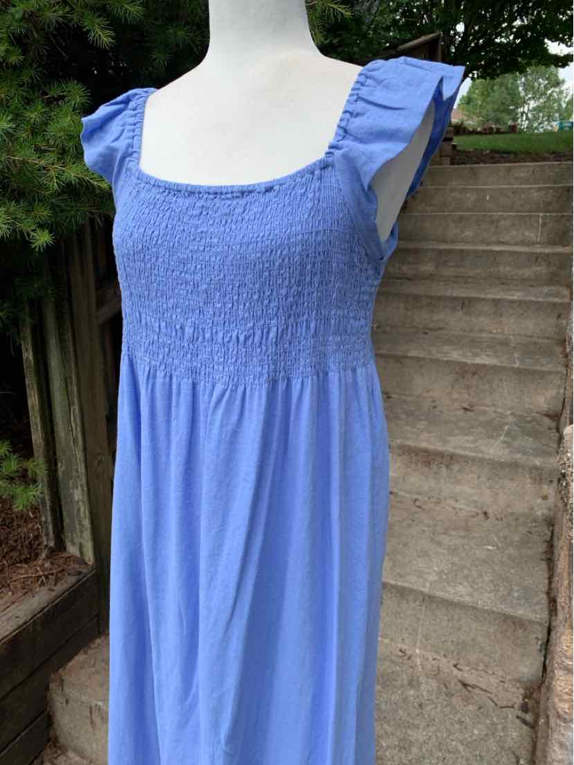 Light blue sleeveless dress with smocked bodice and square neckline on mannequin outdoors.